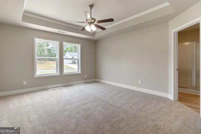 an empty room with a ceiling fan and windows