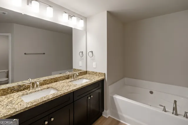 a bathroom with a granite countertop bathtub sink double and mirror