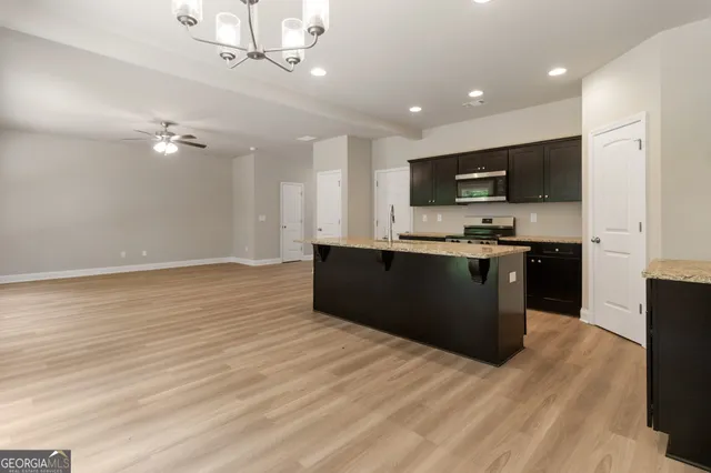 a kitchen with kitchen island stainless steel appliances a sink cabinets and a wooden floor