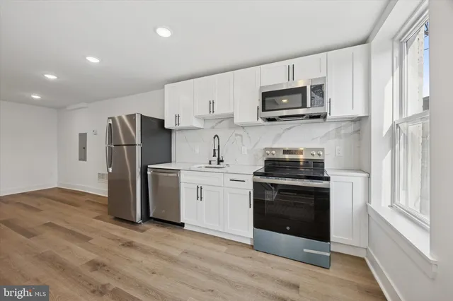 a kitchen with stainless steel appliances a stove a microwave and white cabinets
