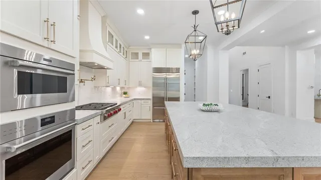 a large kitchen with stainless steel appliances granite countertop a lot of counter space and wooden floor