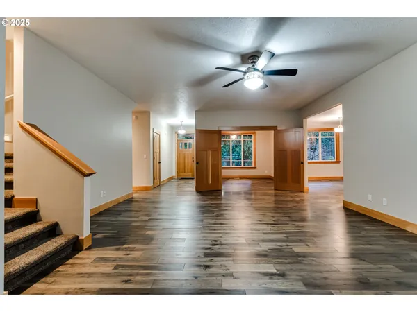 a view of an empty room with wooden floor and staircase