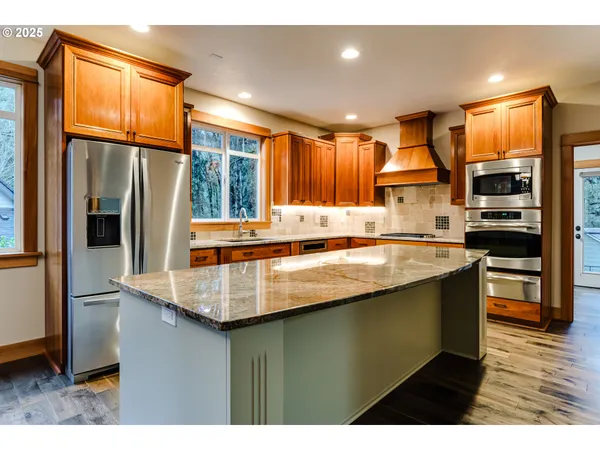 a kitchen with stainless steel appliances granite countertop a refrigerator a sink and a stove