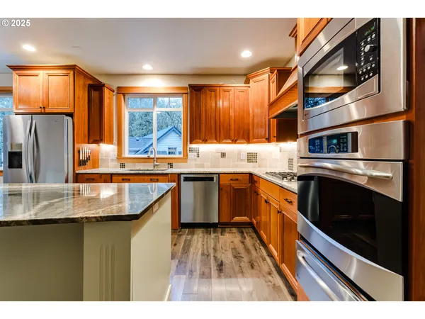 a kitchen with stainless steel appliances granite countertop a stove a sink and a microwave