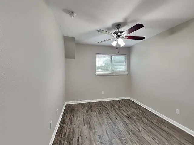 a view of a room with wooden floor and a ceiling fan