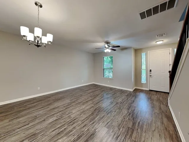 a view of an empty room with wooden floor and window