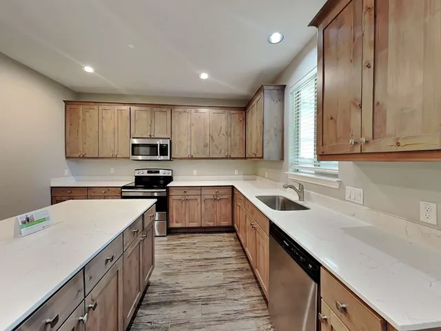 a kitchen with stainless steel appliances granite countertop refrigerator a sink dishwasher a stove top oven a refrigerator and cabinets with wooden floor