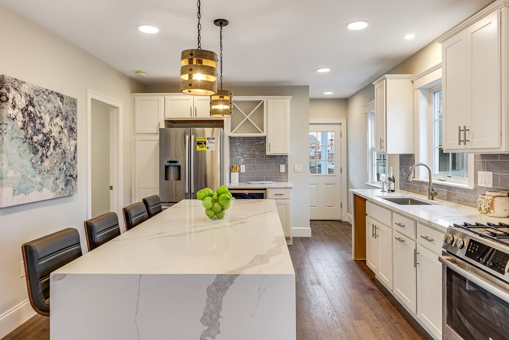 94 Marathon Street, Unit 1 Arlington, MA 02474 - Photo 5 of 24 a large kitchen with kitchen island a large counter top space a sink stainless steel appliances and cabinets