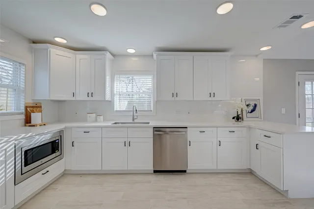 a kitchen with a sink white cabinets and white appliances