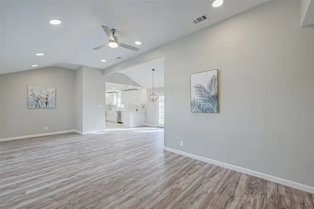 an empty room with wooden floor and a ceiling fan