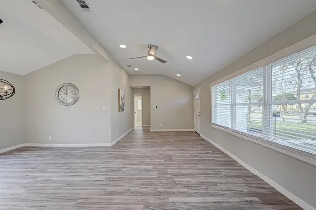 a view of an empty room with a window and wooden floor