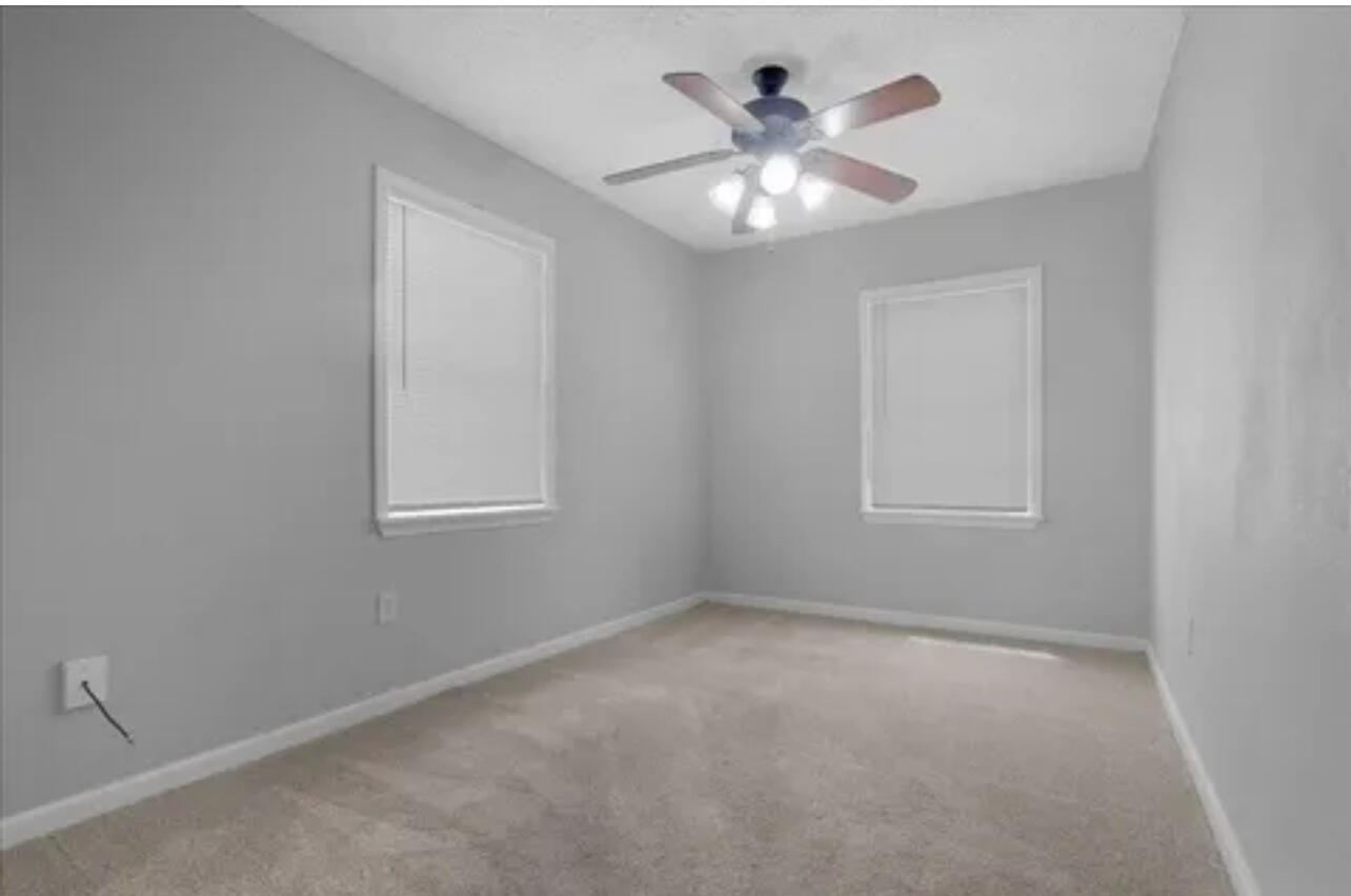 3302 Bates Street Lubbock, TX 79415 - Photo 5 of 9 an empty room with a chandelier fan and windows