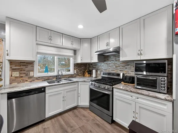 a kitchen with granite countertop white cabinets and white stainless steel appliances
