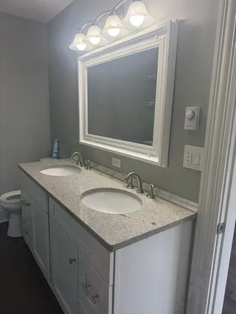 a bathroom with a granite countertop sink a large mirror and a toilet