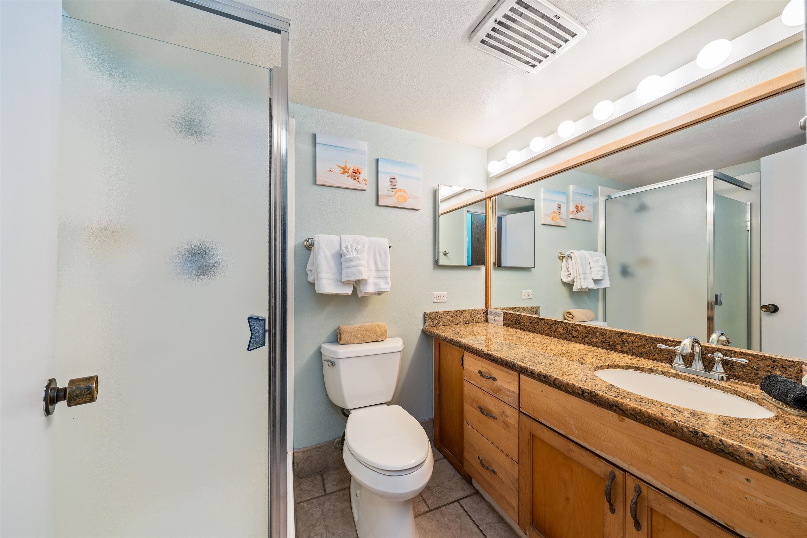 3615 Lower Honoapiilani Road, Unit 123 Lahaina, HI 96761 - Photo 36 of 41 a bathroom with a granite countertop toilet a sink and a mirror