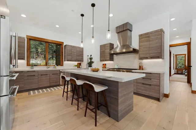 a kitchen with stainless steel appliances granite countertop a stove a sink a oven and a refrigerator with wooden floor