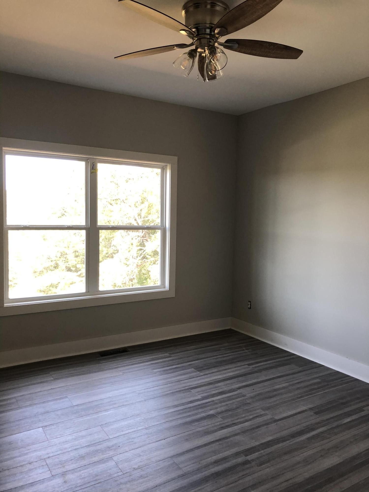 255 Clear Creek Road Kodak, TN 37764 - Photo 7 of 8 an empty room with wooden floor fan and windows