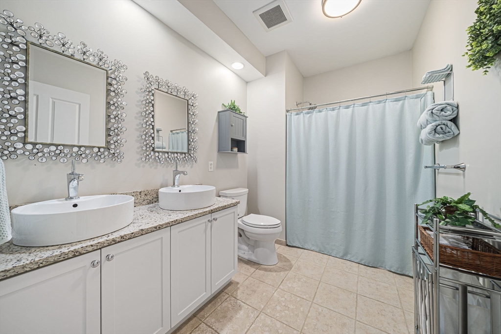 59 Walpole Street, Unit 115 Canton, MA 02021 - Photo 13 of 41 a bathroom with a granite countertop sink a toilet and a mirror