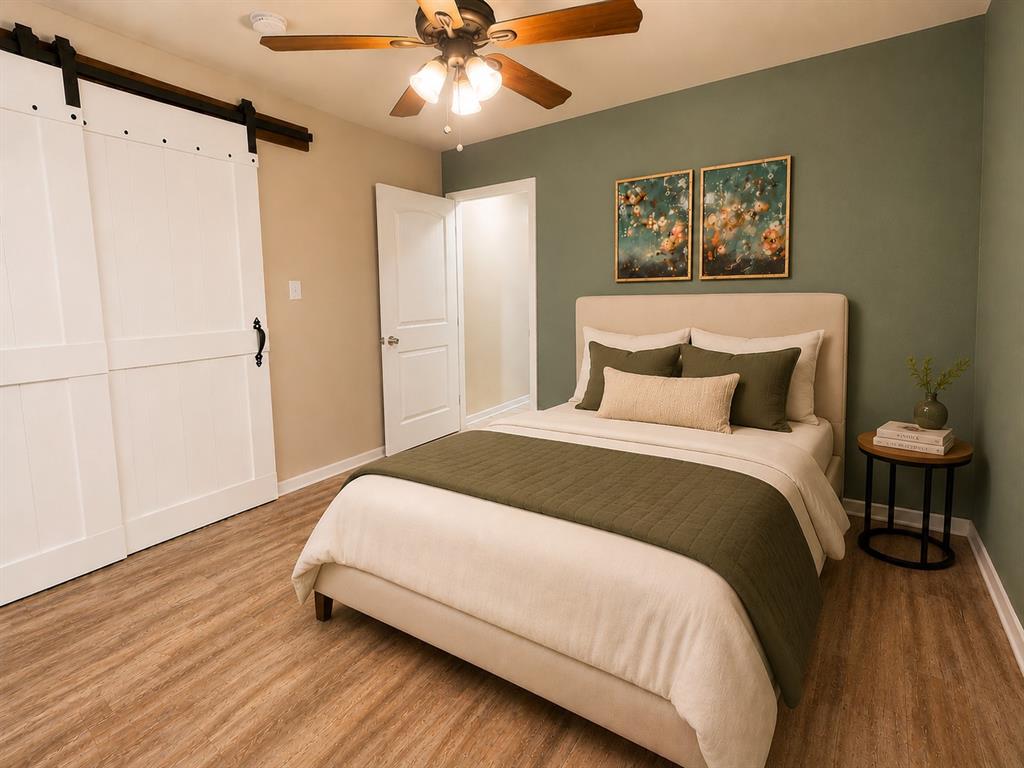 420 Sessums Road Springtown, TX 76082 - Photo 31 of 40 Spacious room featuring wood-finish flooring, a ceiling fan with light fixture, and a feature wall with a muted green finish-virtually staged.