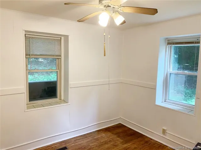 an empty room with a window and chandelier fan