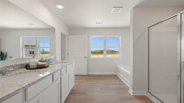 a view of a hallway with wooden floor and a bathroom