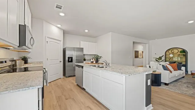 a kitchen with stainless steel appliances granite countertop a sink dishwasher stove top oven and refrigerator with wooden floor