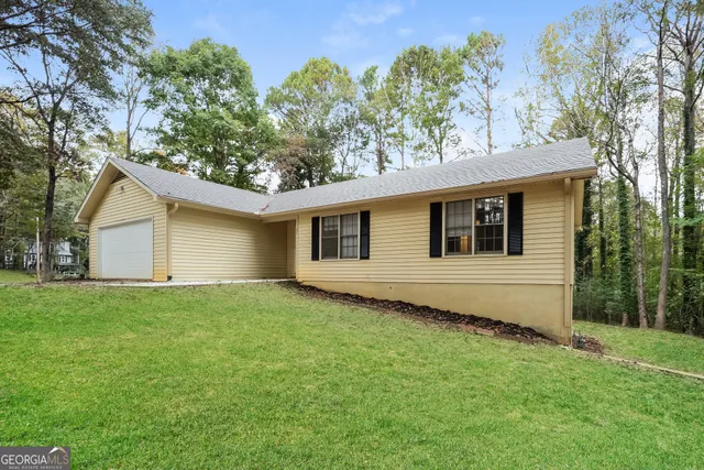 a view of a backyard with plants and large tree