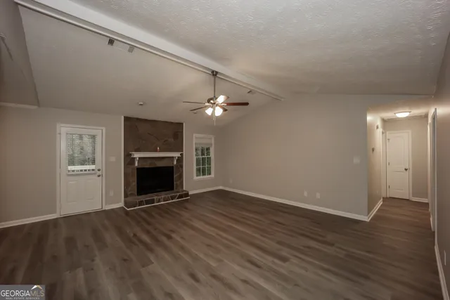 a view of an empty room with wooden floor fireplace and a window