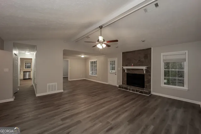 a view of an empty room with wooden floor fireplace and a window