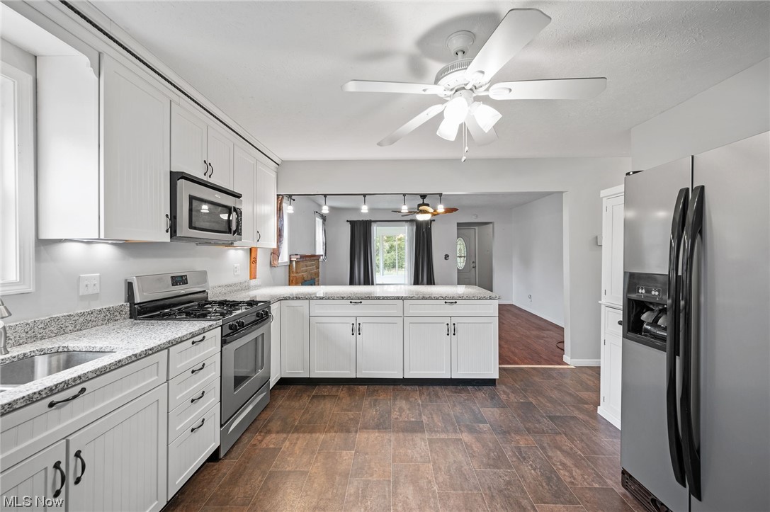 228 Cavalry Road Vermilion, OH 44089 - Photo 13 of 34 Kitchen with dark hardwood floors, light countertops, white cabinetry, track lighting, ceiling fan, and stainless steel appliances