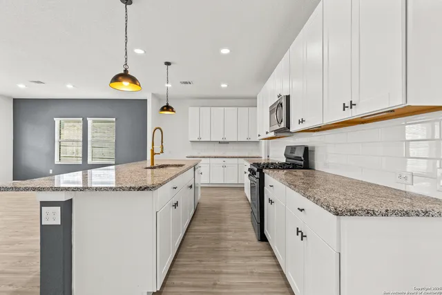 a kitchen with stainless steel appliances granite countertop a sink a stove and cabinets
