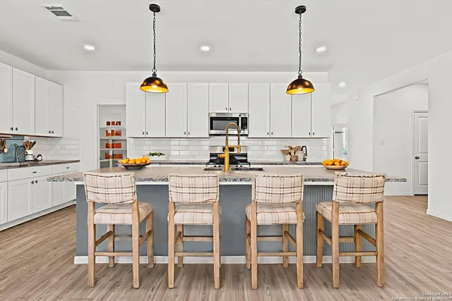 a kitchen with stainless steel appliances granite countertop a dining table chairs refrigerator and microwave