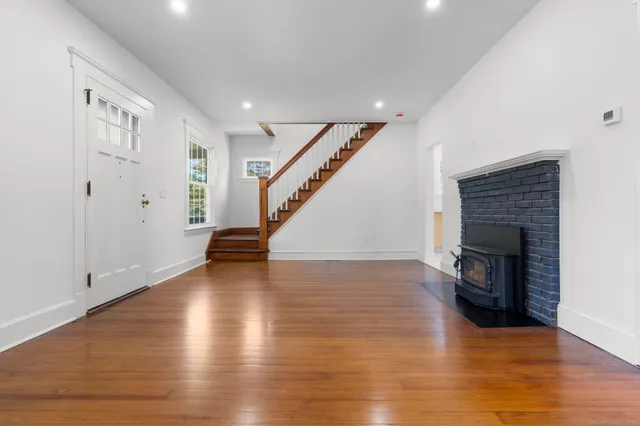 a view of an empty room with wooden floor fire place
