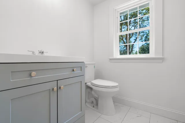 a bathroom with a sink a toilet and a window