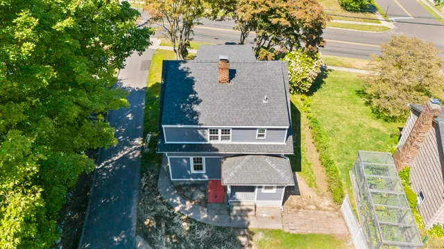 an aerial view of a house with swimming pool and large trees