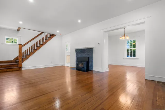 a view of an empty room with wooden floor fireplace and a window