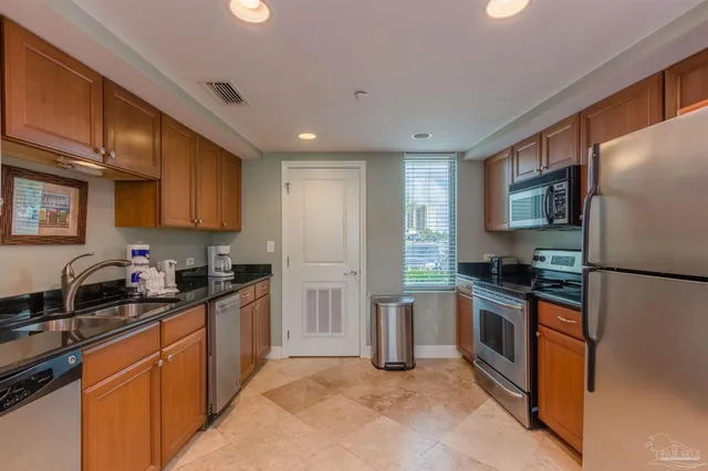 a kitchen with granite countertop stainless steel appliances a sink a stove and a refrigerator