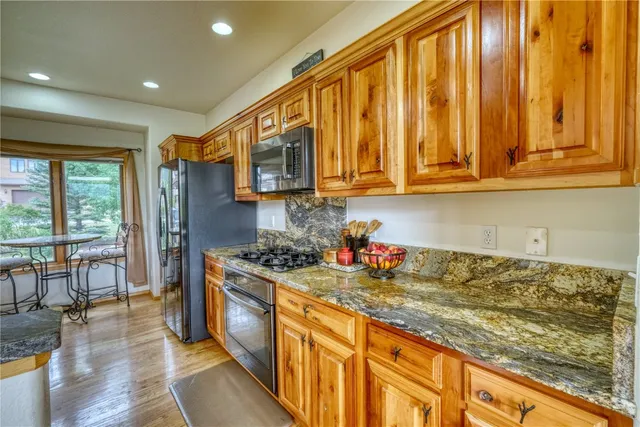 a kitchen with stainless steel appliances granite countertop a sink stove cabinets and wooden floor