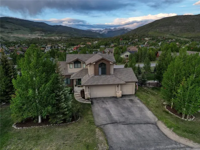 a front view of a house with a yard and mountain view in back