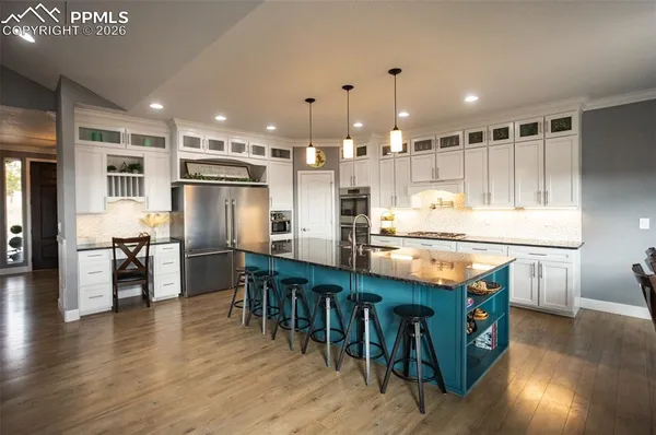a kitchen with stainless steel appliances granite countertop a table chairs and a refrigerator