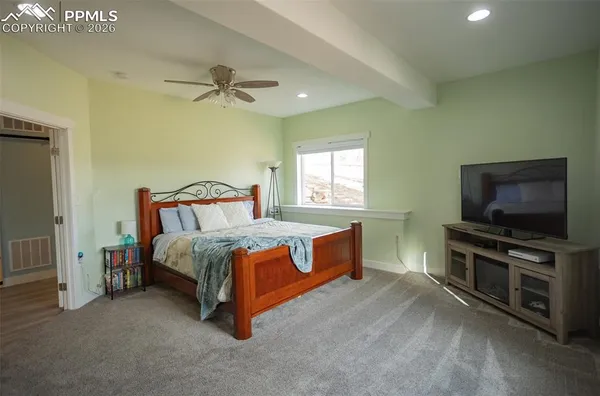 a spacious bedroom with a bed and a flat screen tv
