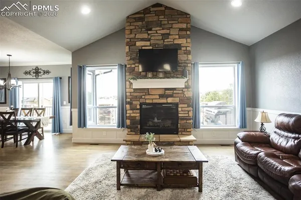 a living room with furniture a fireplace and a floor to ceiling window