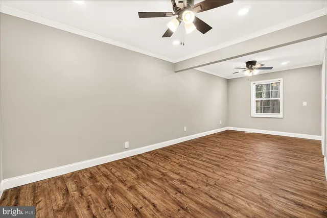 an empty room with wooden floor chandelier fan and windows