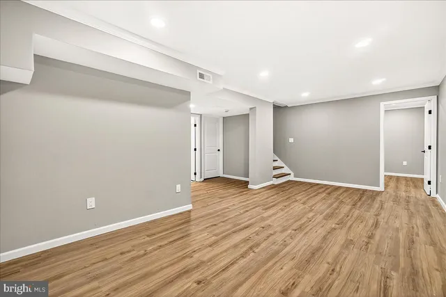 a view of an empty room with wooden floor and window