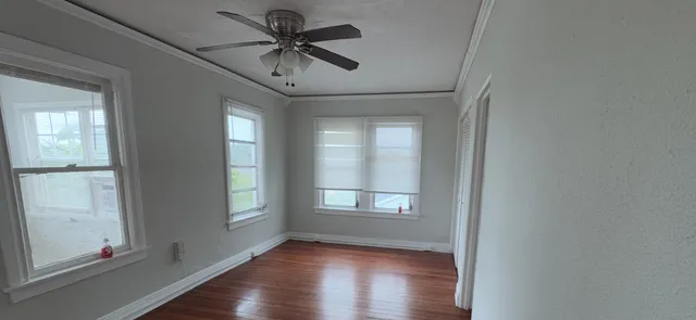a view of an empty room with a window and wooden floor