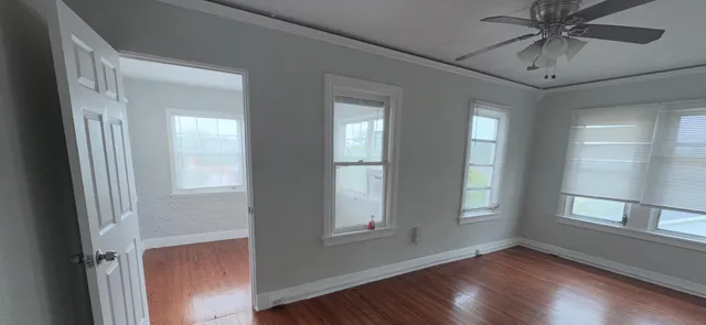 a view of an empty room with chandelier fan and fire place