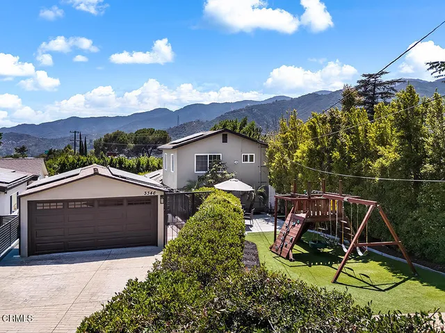 a view of house with backyard and sitting area