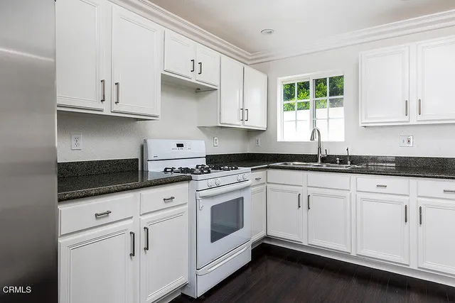 a kitchen with granite countertop white cabinets and white appliances