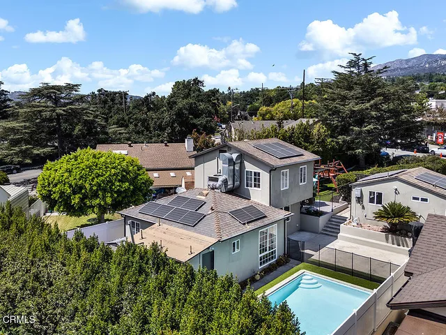 an aerial view of a house with swimming pool garden and mountain view in back