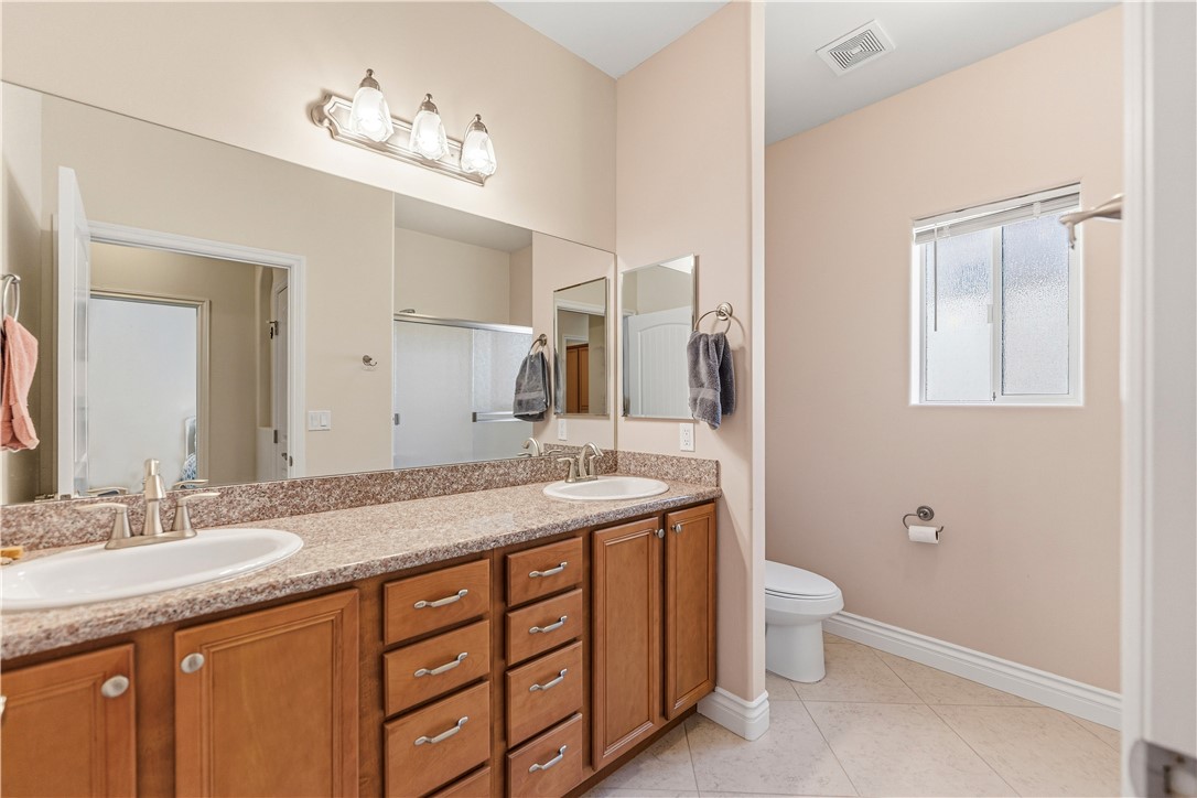 3315 Rainbow Mine Road Kingman, AZ 86401 - Photo 33 of 54 Bathroom featuring a dual sink vanity with wood cabinetry, a large mirror, and tiled flooring